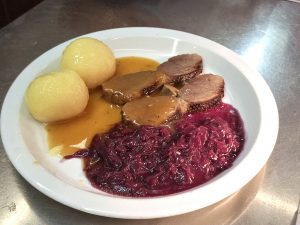 Rinderbraten mit Rotkohl und Kartoffeln auf Teller.