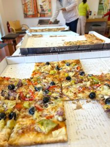 Verschiedene Pizzen in Kartons auf einem Tisch.