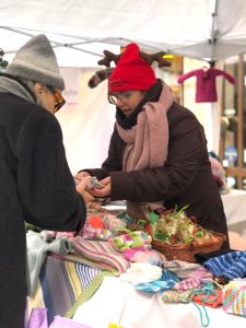 Menschen auf Weihnachtsmarkt mit gestrickten Waren.