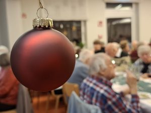 Rote Weihnachtskugel bei älteren Menschen in Restaurant
