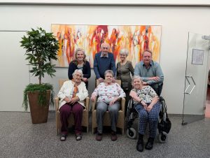 Seniorengruppe vor abstraktem Gemälde im Innenraum